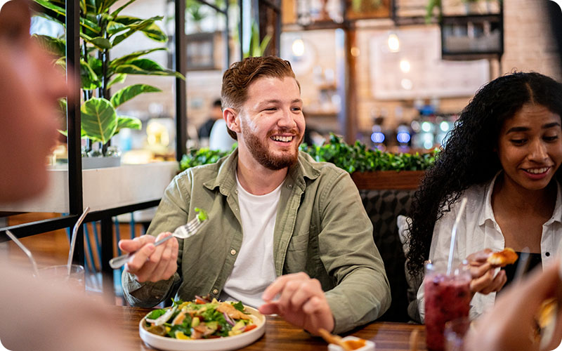 Man eating a salad surrounded by friends